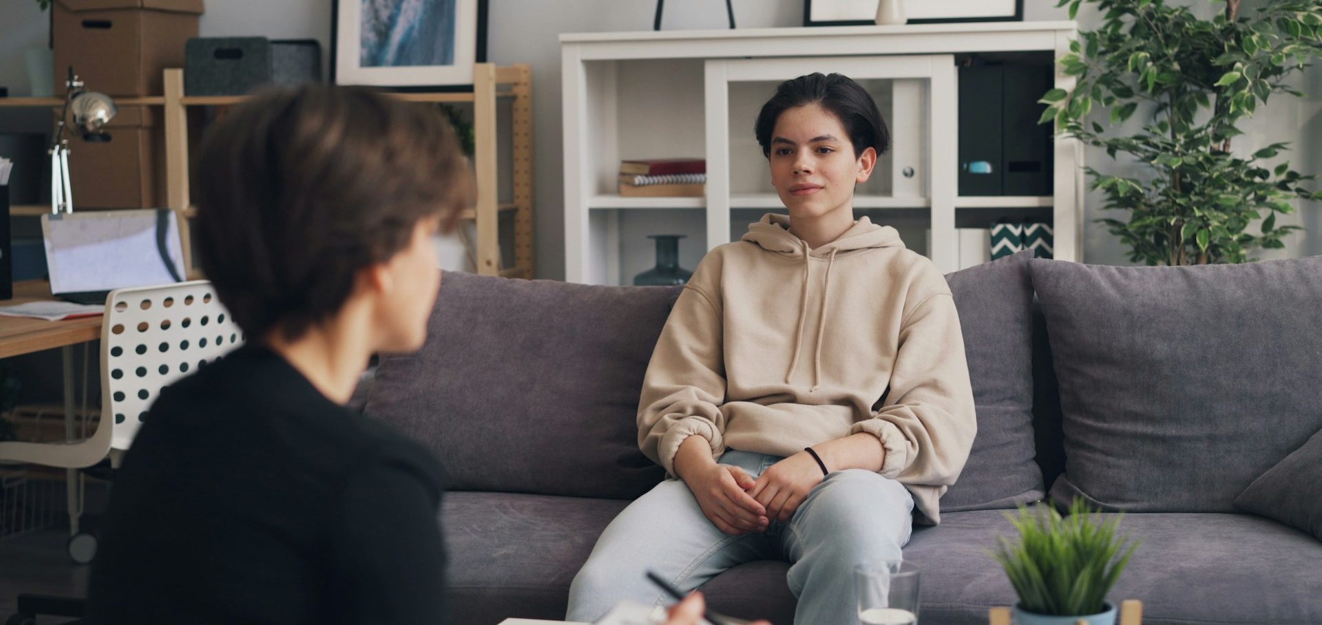 young person on comfy grey sofa speaking with therapist.